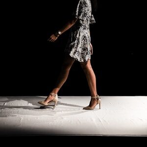 woman wearing black and white floral dress walks inside dark room