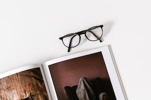 eyeglasses on top of photo album on white surface