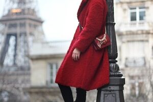 woman in red coat leaning on post lamp