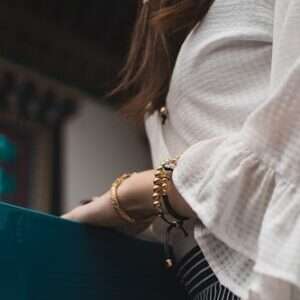 woman wearing white top and wearing gold-colored bracelets