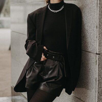 woman in black long sleeve dress leaning on gray concrete wall during daytime