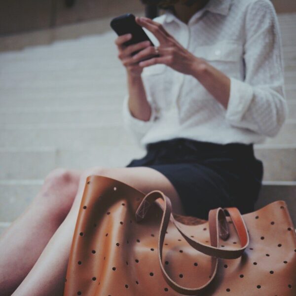 woman sitting on concrete stair beside brown leather tote bag
