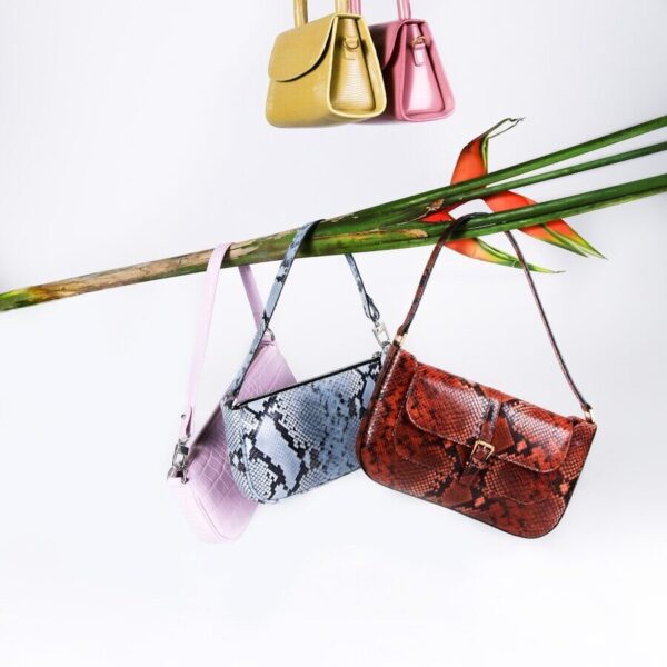 brown leather sling bag hanged on green and red clothes hanger