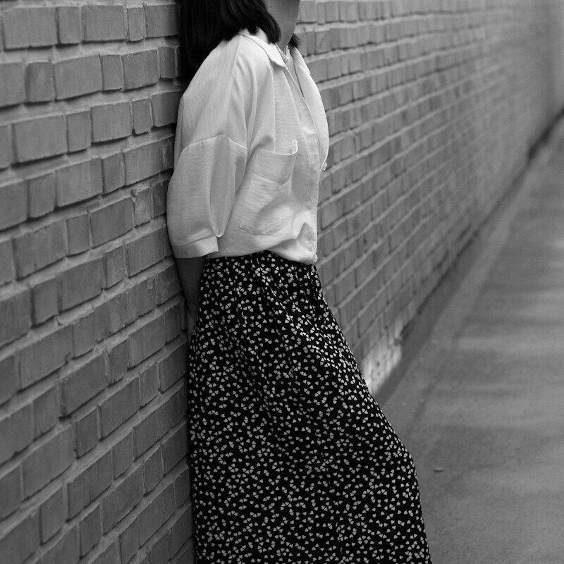 A woman leaning against a brick wall