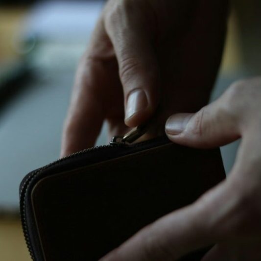 a person opening a wallet on a table